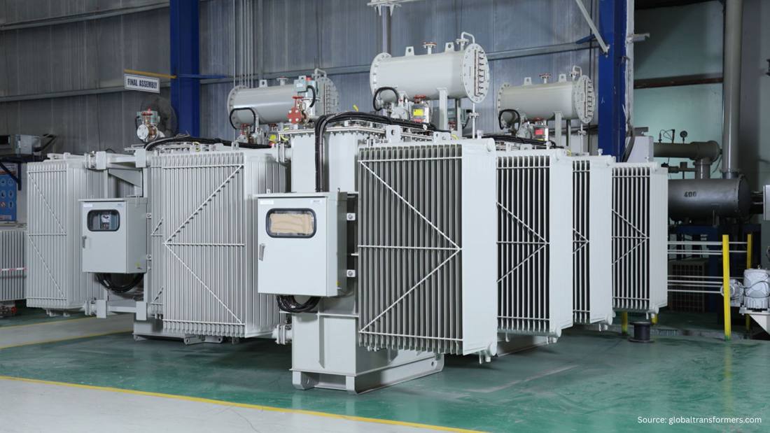 Oil-filled power transformer with radiators and conservator tanks in a factory hall